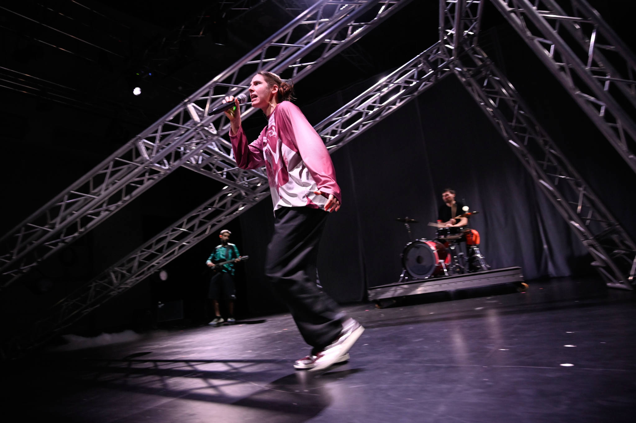 Drei Personen auf der Bühne, eine singt, eine spielt Schlagzeug und eine Gitarre.