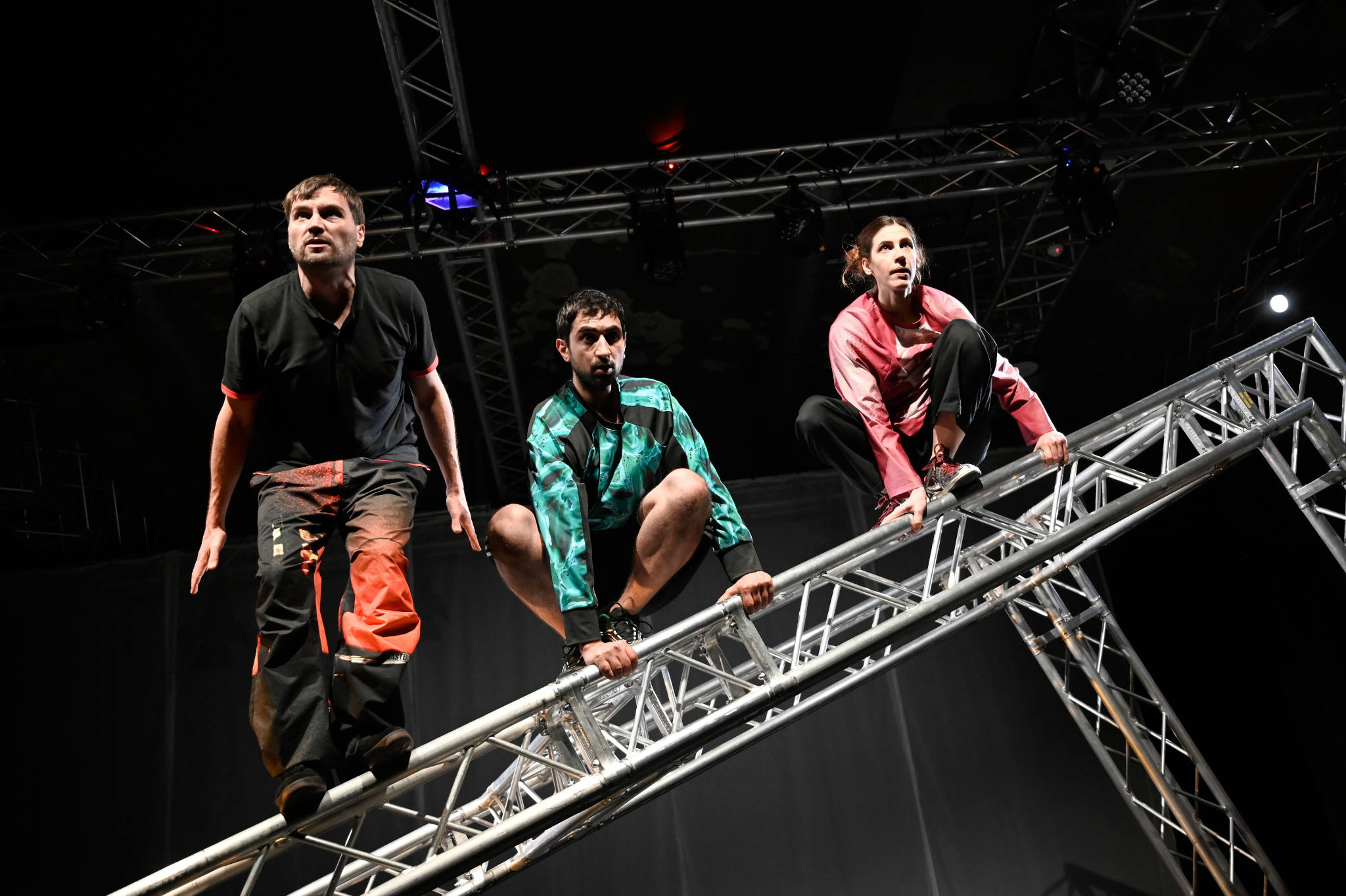 Drei Personen klettern auf einem schrägen Gerüst.