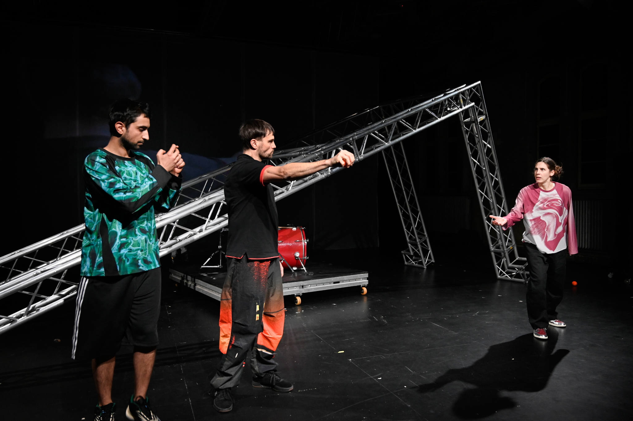 Drei Personen stehen vor einem schrägen Gerüst.